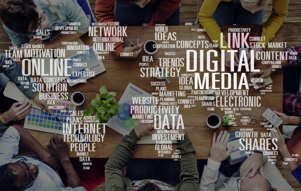 Team meeting at a table overlaid with a digital marketing word cloud