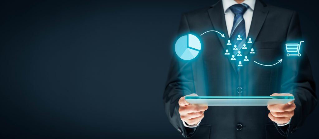 Businessman holding a tablet projecting glowing network and chart icons in the dark
