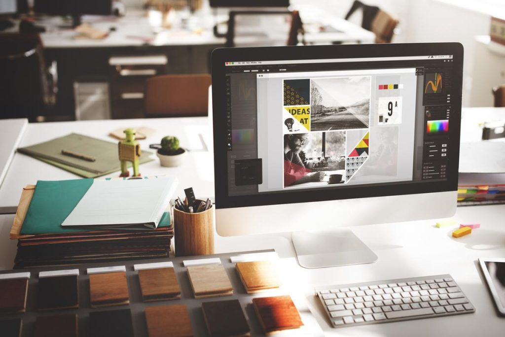 Designer's desk with a mood board on a desktop monitor and wood finish samples