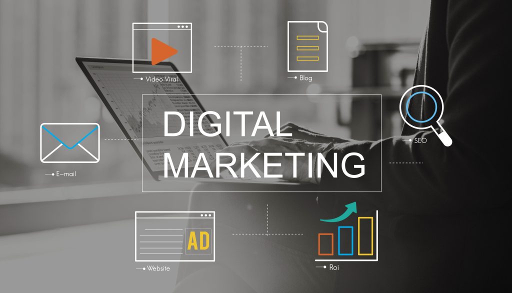 Words Digital Marketing with email, ad and analytics icons over a person at a laptop