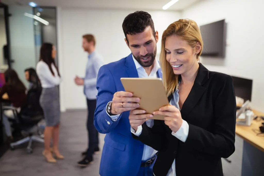 Man and woman looking at a tablet in an office hallway