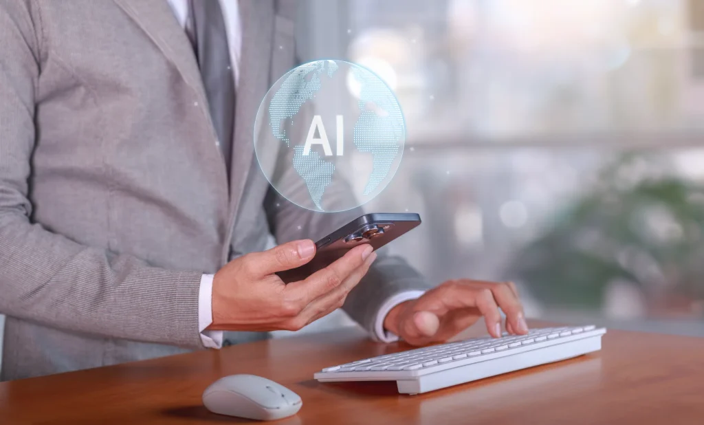 Businessman holding a smartphone with a glowing AI icon above it, keyboard on the desk