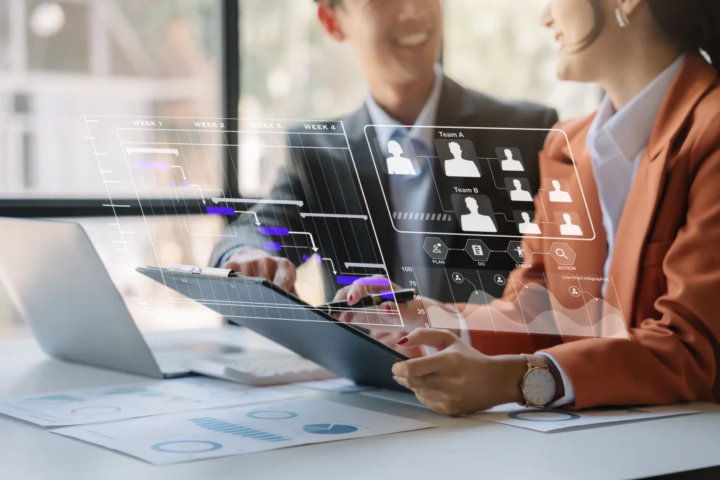 Business people at a table with holographic profile icons over a laptop and tablet
