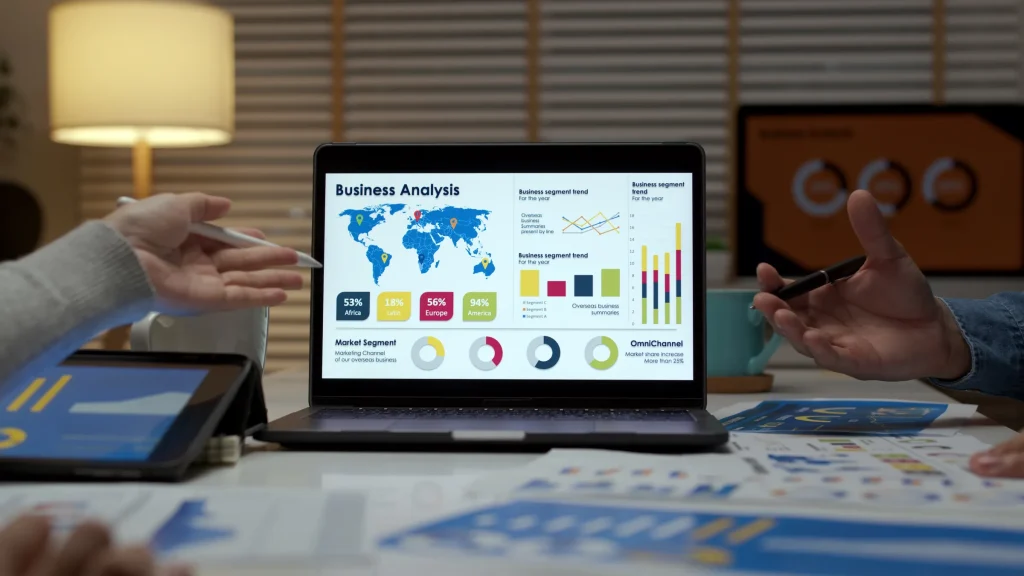 Laptop showing a business analysis dashboard with a world map as people point at it