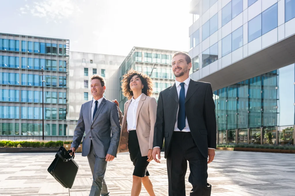 Three business people walking outside a modern glass office building