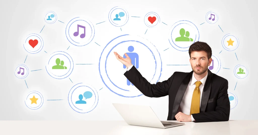 Businessman at a laptop with social media icons connected around him