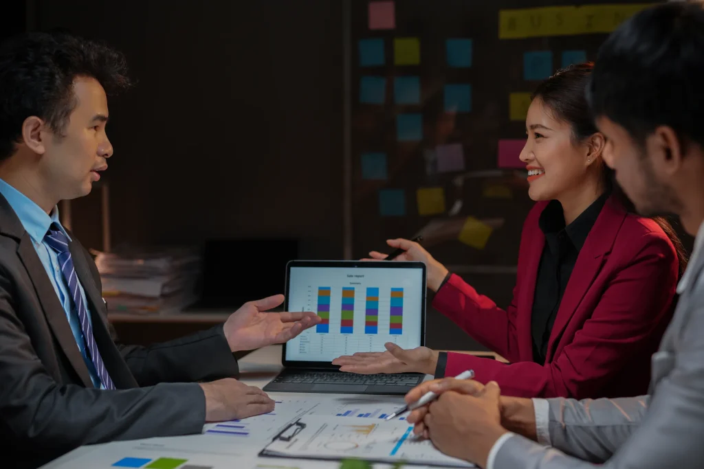 Man showing a bar chart on a tablet to colleagues in an office with sticky notes