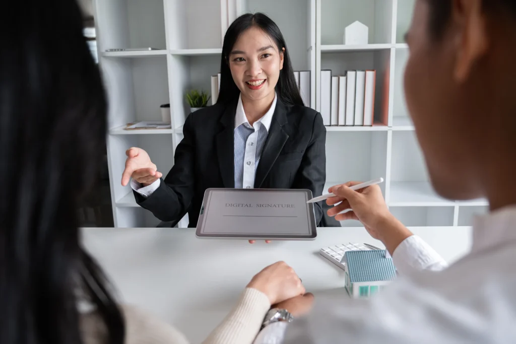 Businesswoman with a tablet meeting a couple at a desk with a small house model