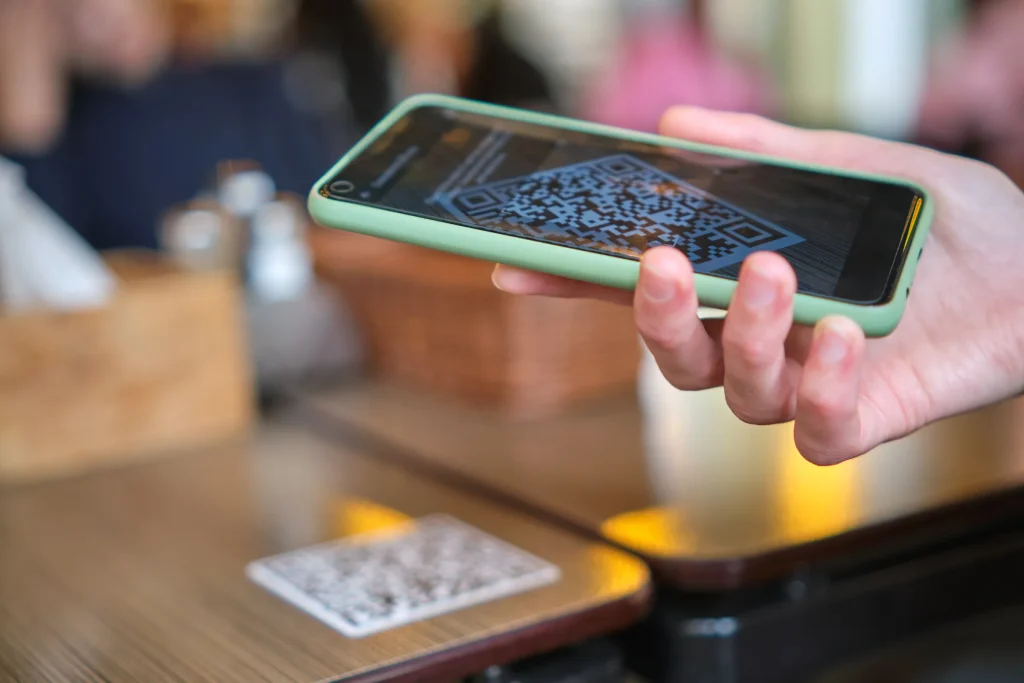 Hand holding a smartphone to scan a QR code at a restaurant table