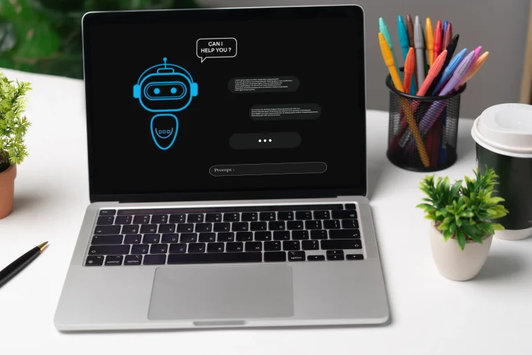 Laptop on a white desk showing a chatbot interface with a robot icon