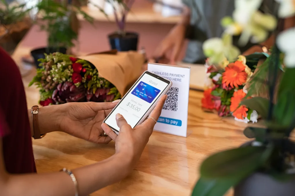 Customer holding a phone to pay at a flower shop counter