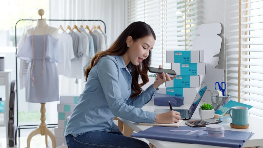 Young woman running an online clothing business from home with a laptop